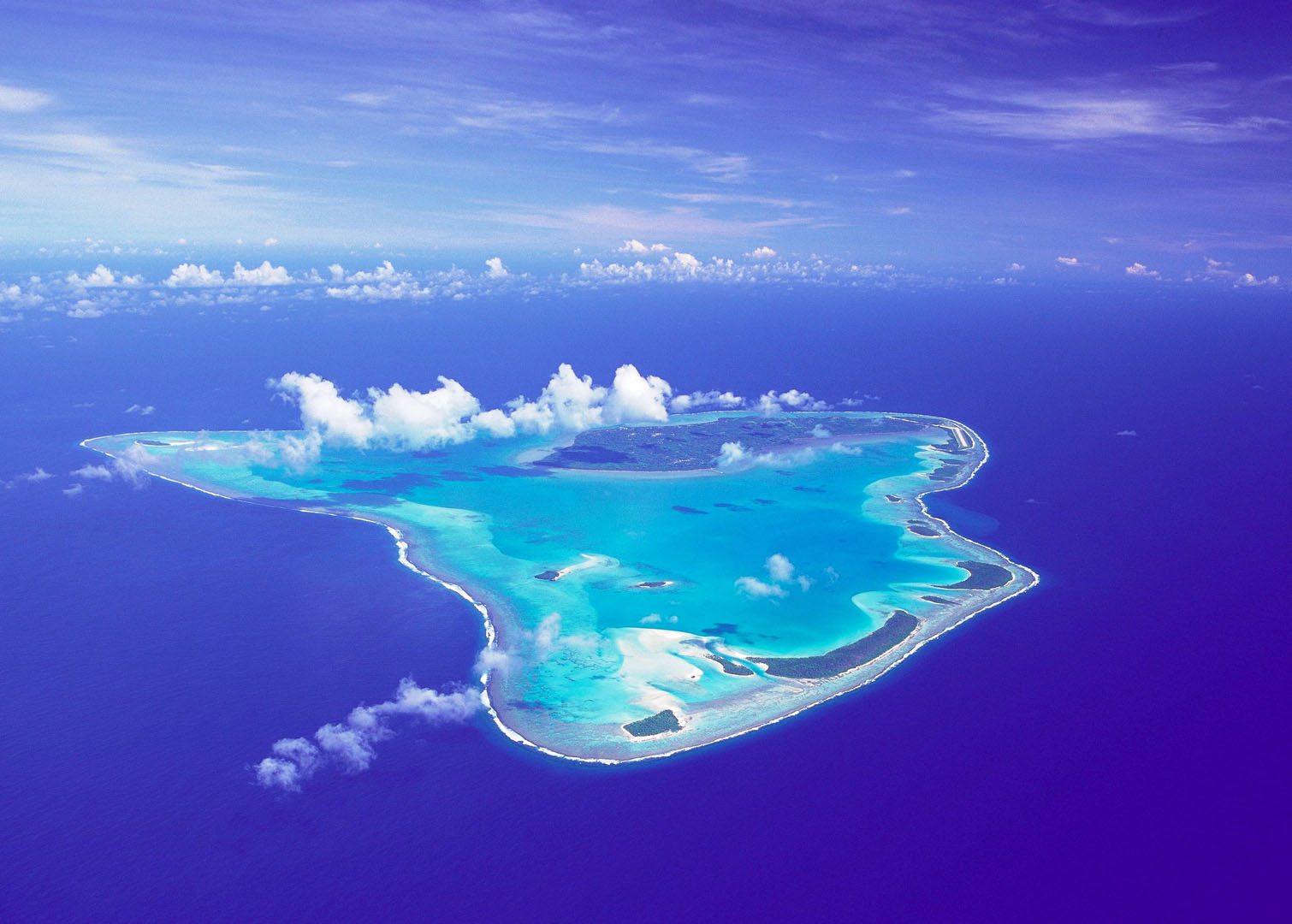 Stunning aerial image of Aitutaki Island featuring its natural beauty that offers luminous aqua lagoons, set amidst the deep blue ocean