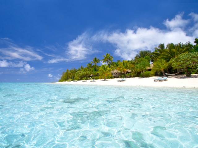 Lagoon view sun-deck loungers set up in pairs on a long-stretched white sandy beach