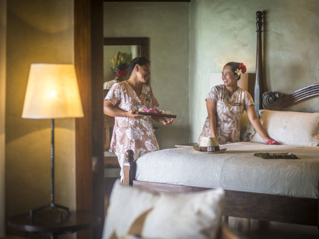 Resort attendants happily servicing the Ultimate Beachfront Villa, placing flowers and arrival gifts on the bed