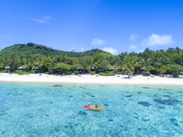 Aerial image of two female guests kayaking on the lagoon in front of the Resort on a beautiful bright day