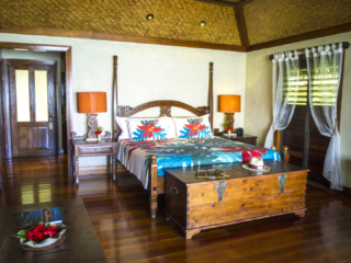 A lovely image of the Premium Beachfront Bungalow bedroom with a beautiful carved wood bedside lamp on each side of the bed