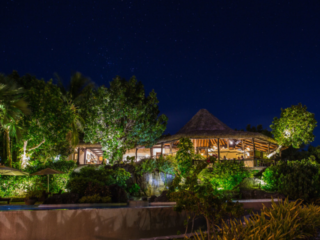 A perfect image of the Rapae Bay Restaurant during night, under the stars, with bright glowing lights illuminating the area and swimming pool nearby