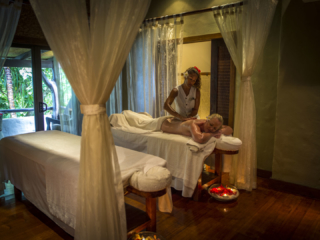 A full view of Spa room, featuring a Spa Therapist performing a body massage on resort guest