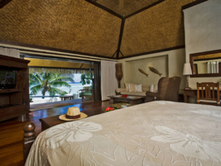 A stunning view of the Ultimate Beachfront Bungalow bedroom overlooking the lagoon that offers different shades of blue