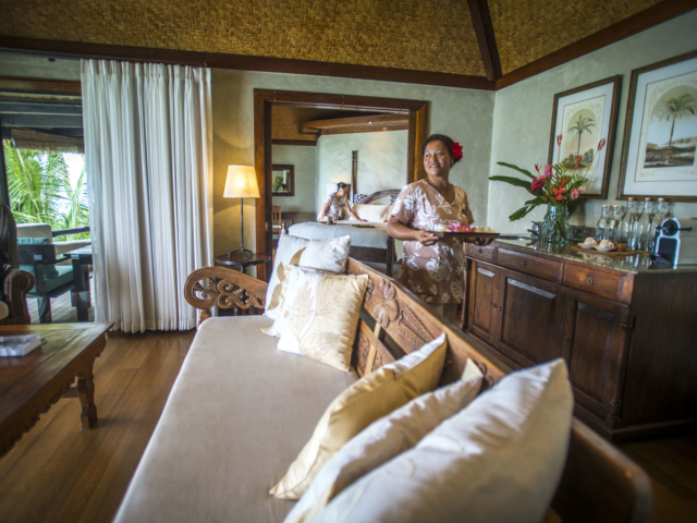 A lovely set up of the Ultimate Beachfront Villa living room with partial view of the bedroom, featuring tropical flowers