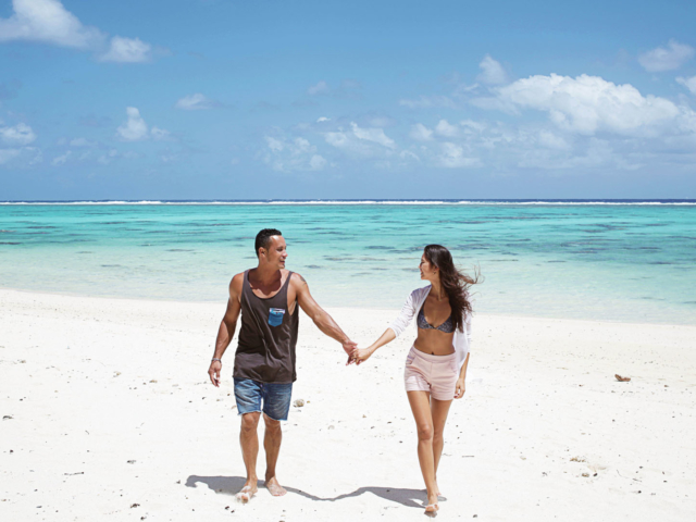 A happy couple hand in hand enjoying a sunny stroll on the beach