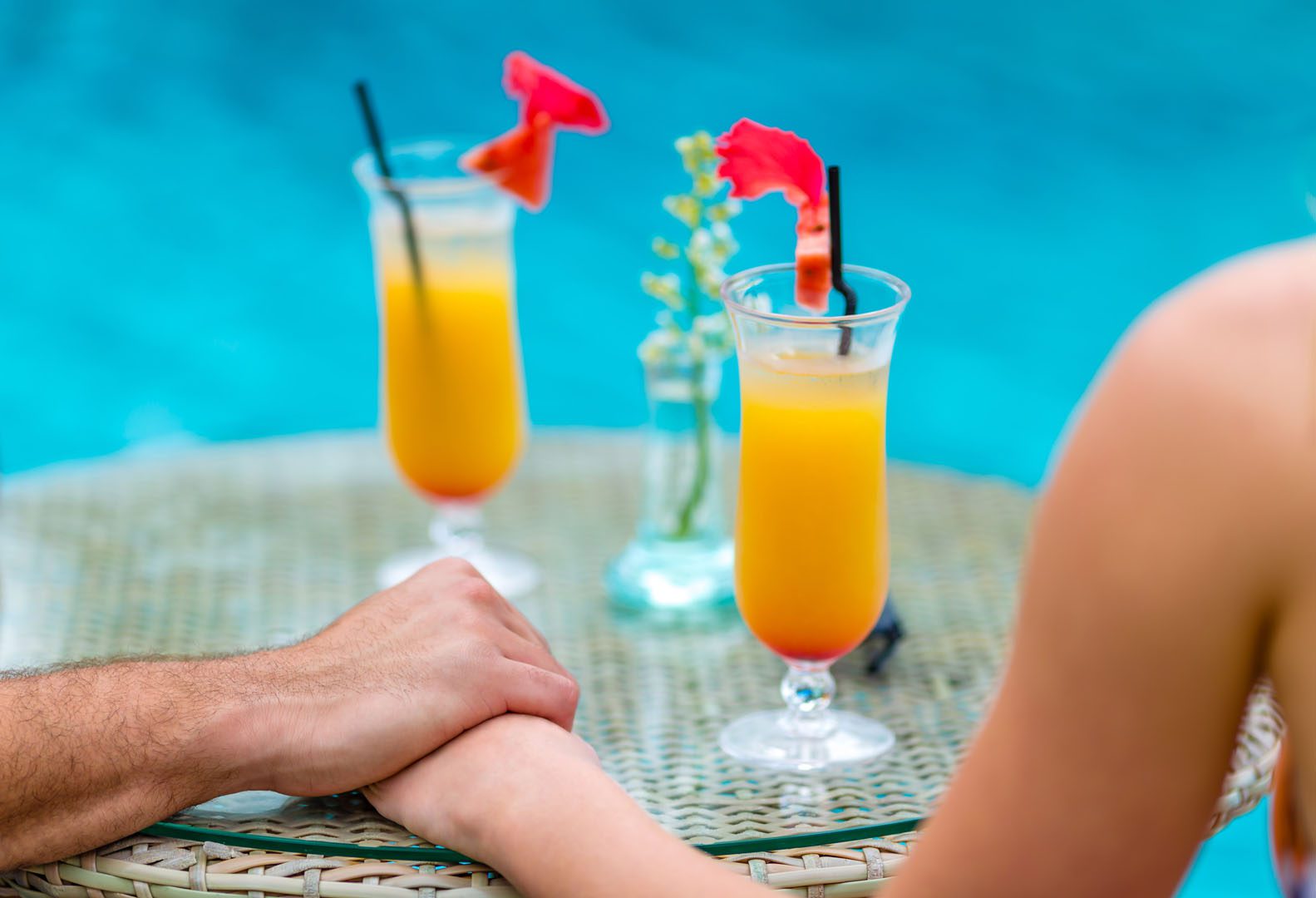 A couple holding hands enjoying cocktails by the pool