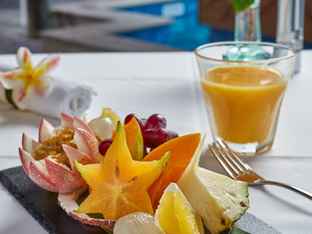A colourful fresh fruit platter and glass of juice in a garden setting