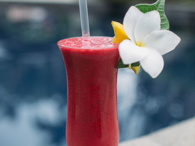 A thirst-quenching image of a beautiful tropical fruit cocktail garnished with frangipani and a slice of fruit
