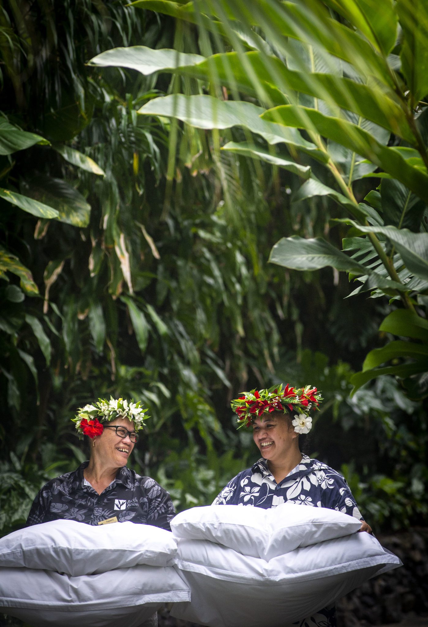 Image of hardworking Resort Attendants happily performing daily routines wearing tropical head eis or tiaras with flowers behind their ear that symbolizes peace and happiness