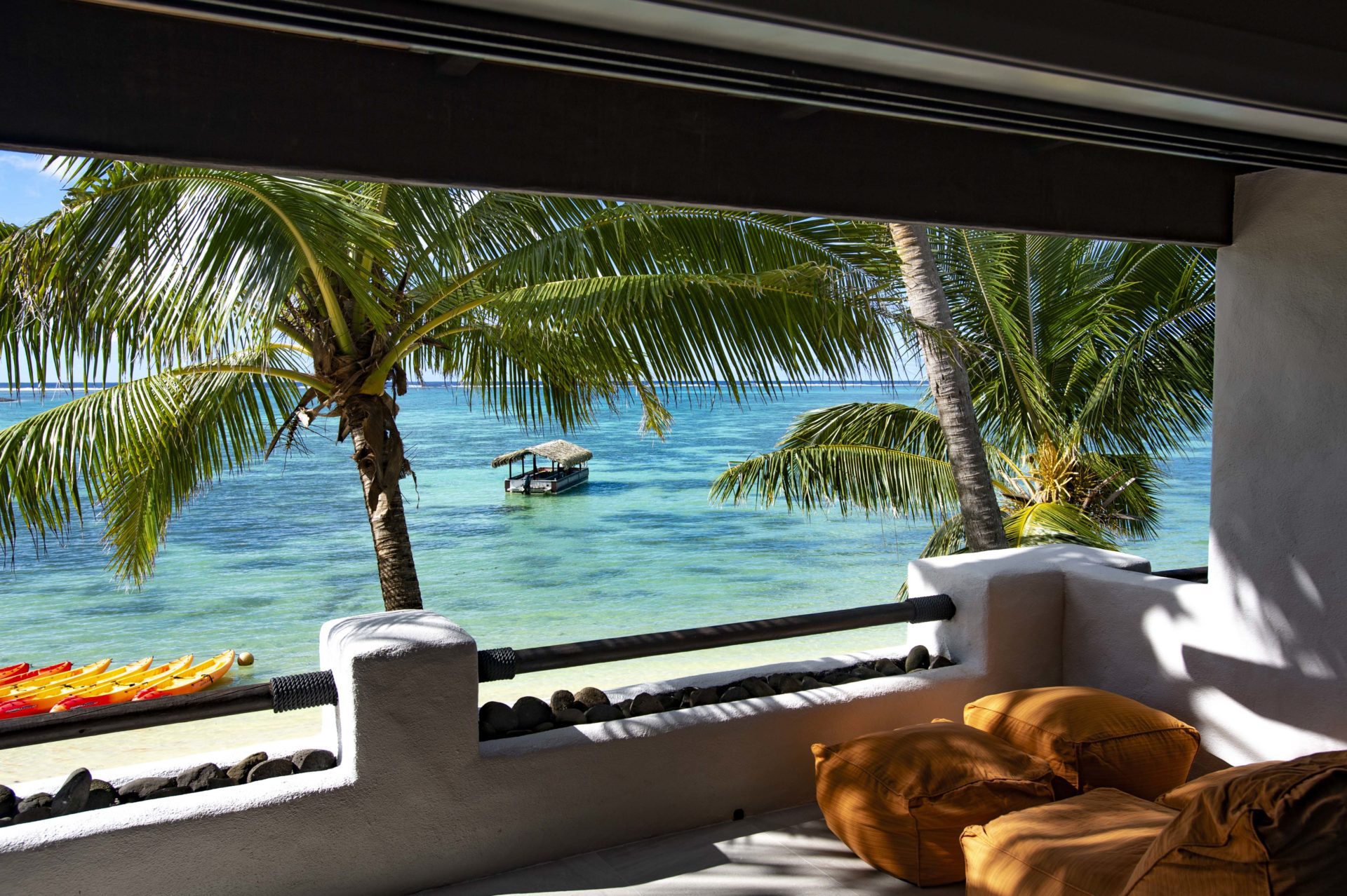 A close up view of the lagoon from the Premium Beachfront Suite private balcony, overlooking trimmed coconut palms that sway in the breeze on a tropical beach