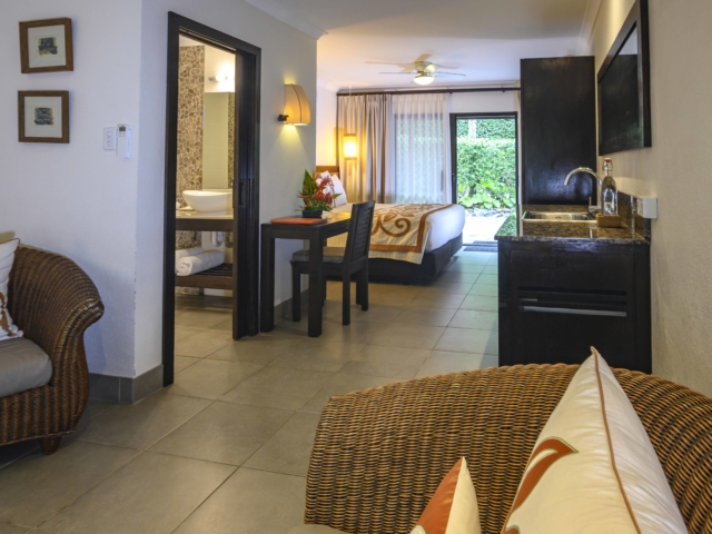 View of the Premium Garden Suite bedroom from the lounge area that overlooks a partial view of the lush garden