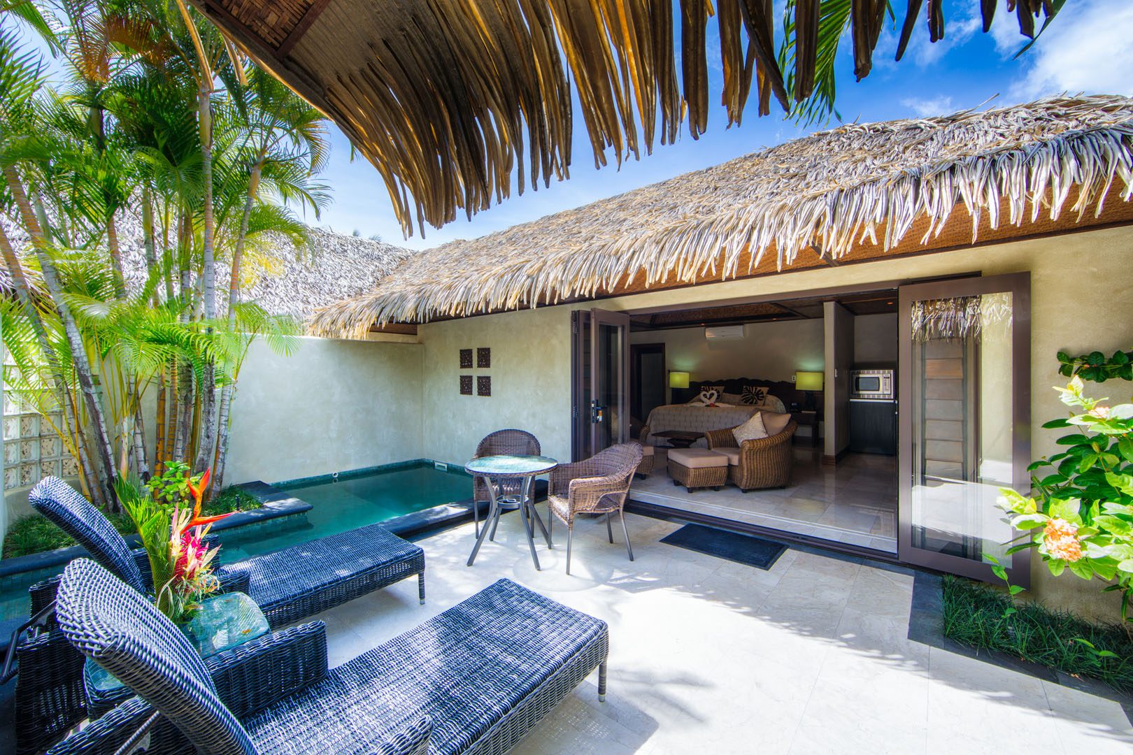 View from the tiled patio area with luxurious outdoor settings and private pool, looking into the Pool villa suite bedroom