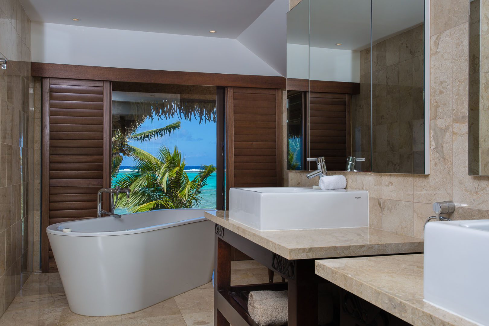 View of the modern Presidential Beachfront Villa Bathroom, with a large bath overlooking a view of the blue lagoon