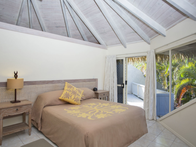 View inside the master bedroom with a beautiful Polynesian bedspread, high white wash ceilings and sliding door connecting to the outside area