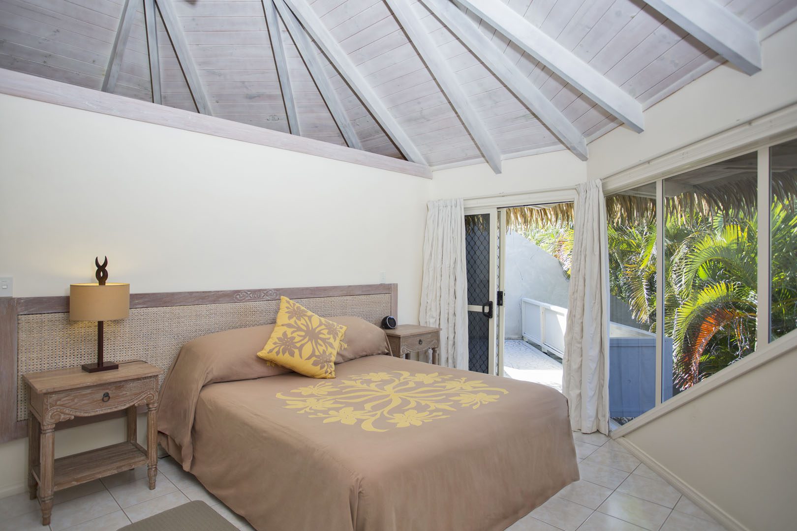View inside the master bedroom with a beautiful Polynesian bedspread, high white wash ceilings and sliding door connecting to the outside area