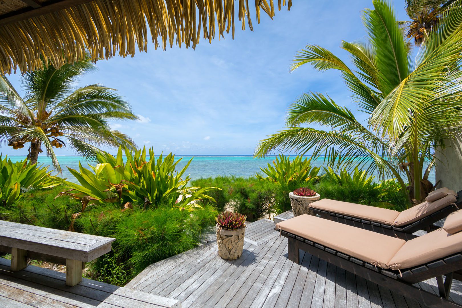 Ultimate beachfront villa view of the deck with loungers set up overlooking the beautiful blue lagoon