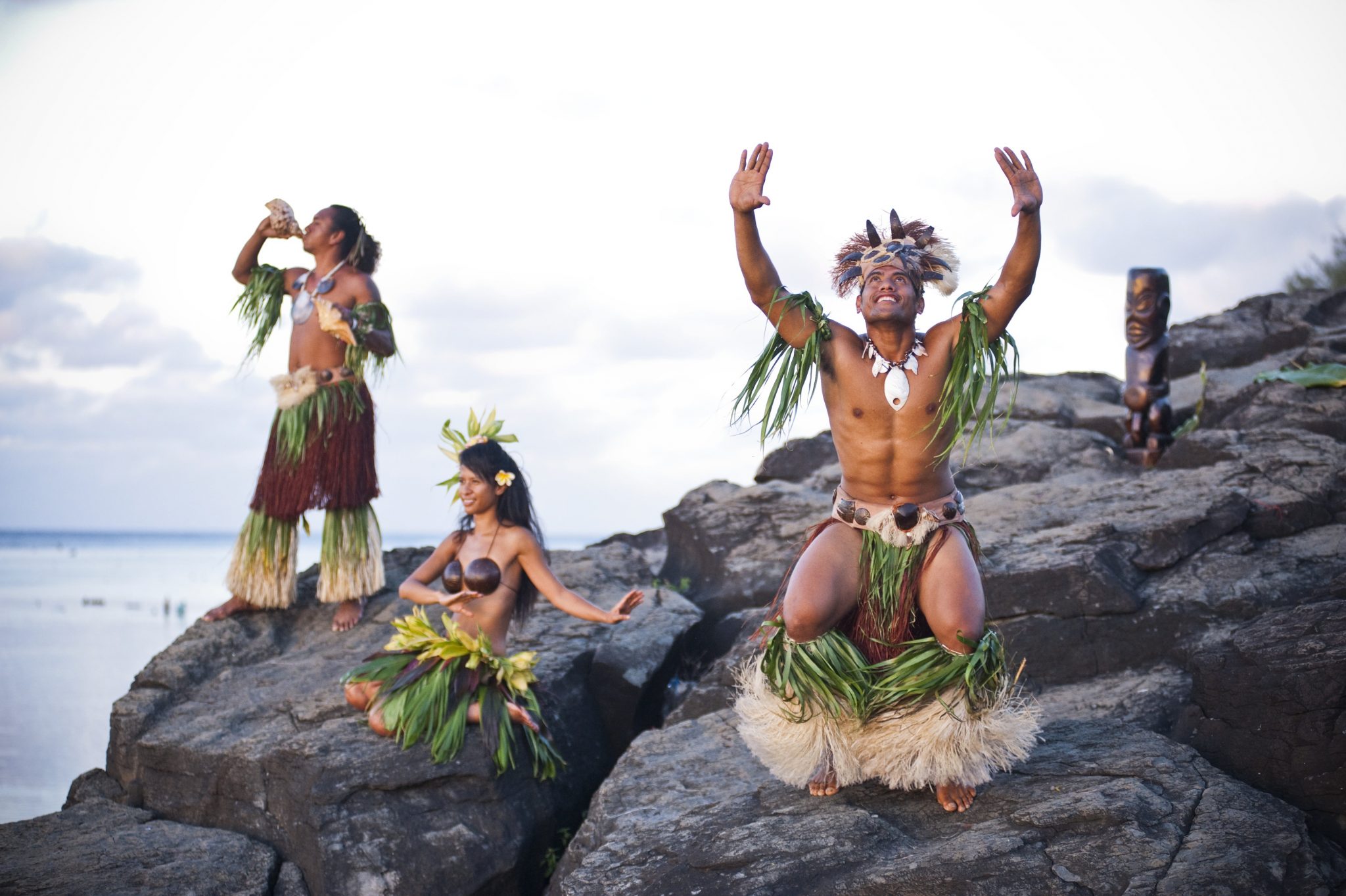three Cook island cultural dancers performing at black rock location on Rarotonga