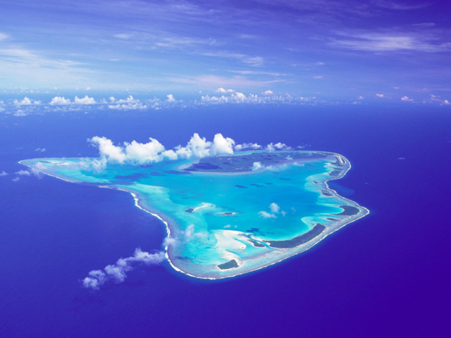 Stunning aerial image of Aitutaki Island featuring its natural beauty that offers luminous aqua lagoons, set amidst the deep blue ocean