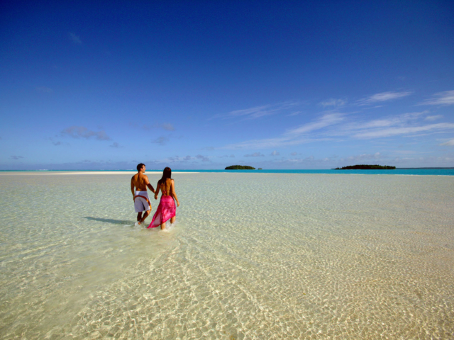 Image of a couple holding hands on One Foot Island featuring the clear white-stretched sand bank