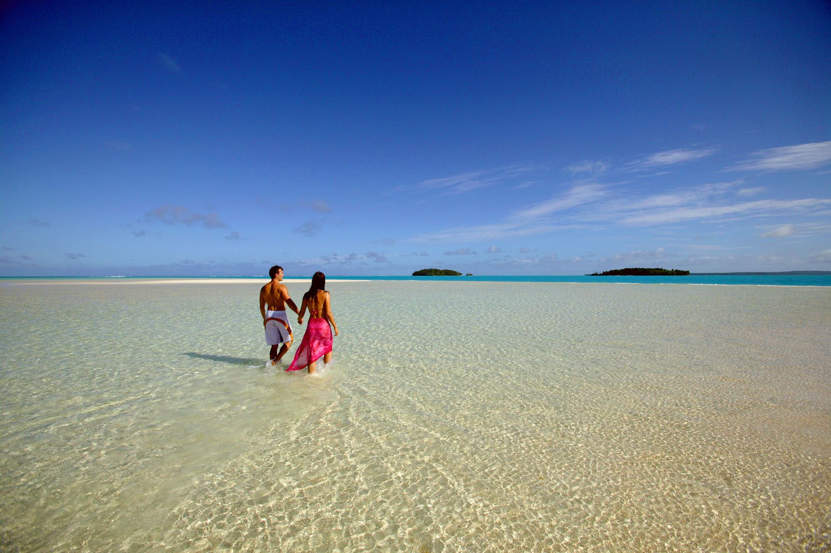 Image of a couple holding hands on One Foot Island featuring the clear white-stretched sand bank