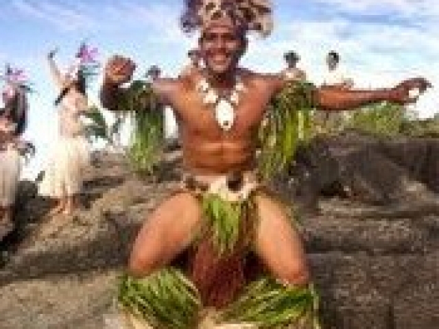 Island warrior dancing with island troupe in background