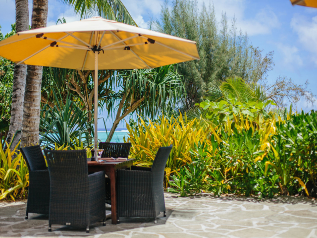 Open-air table setting for four at Black Rock Cafe, partially surrounded by tropical lush garden