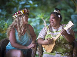 A friendly image of a resort guest enjoying the entertainment performed  solo by a dedicated staff, playing ukulele
