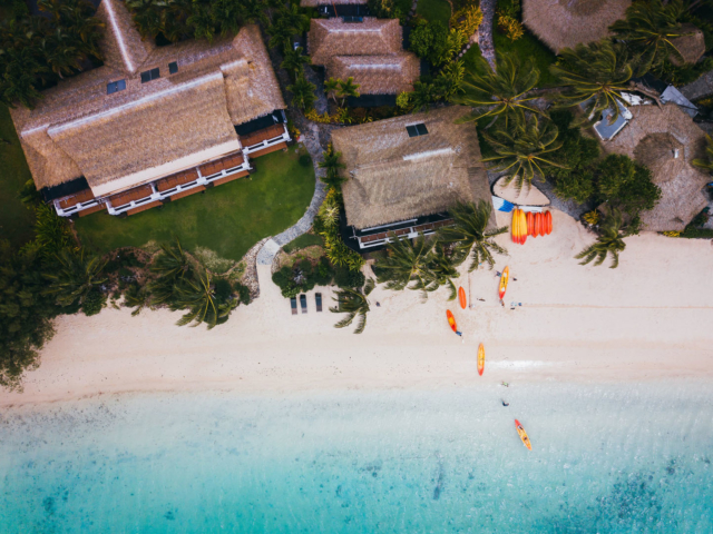 Aerial image of the Resort beachfront focusing on the Beach Hut featuring the colourful orange and yellow kayaks lined up on the beach