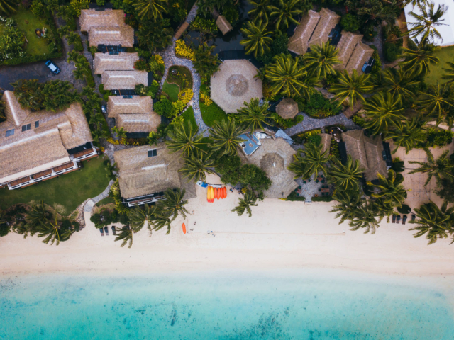 Aerial image of the Resort featuring the thatched roofing, palm trees, the beautiful garden and stunning beach and lagoon in front of the Resort