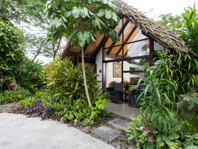 Exterior image of the Premium Family Room featuring a clear pathway to the room and an outside sitting area privately protected by lush tropical garden