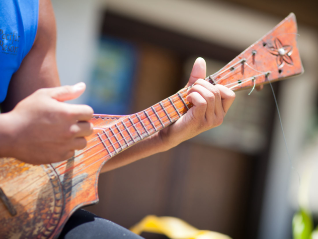 Image of a Resort Attendant holding a locally made ukulele, showing off his strumming skills