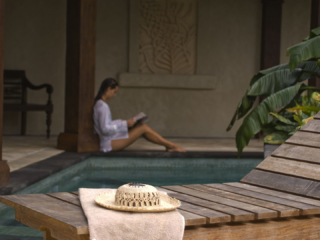 Guest reading a book and relaxing by the luxurious private pool in the presidential villa