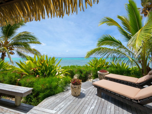 Ultimate beachfront villa view of the deck with loungers set up overlooking the beautiful blue lagoon