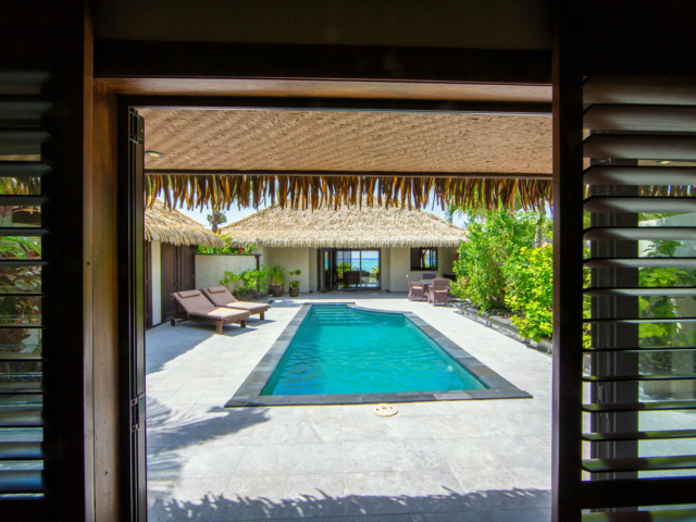 View from the inside of the Ultimate beachfront villa, leading out to the pool area with a lagoon view