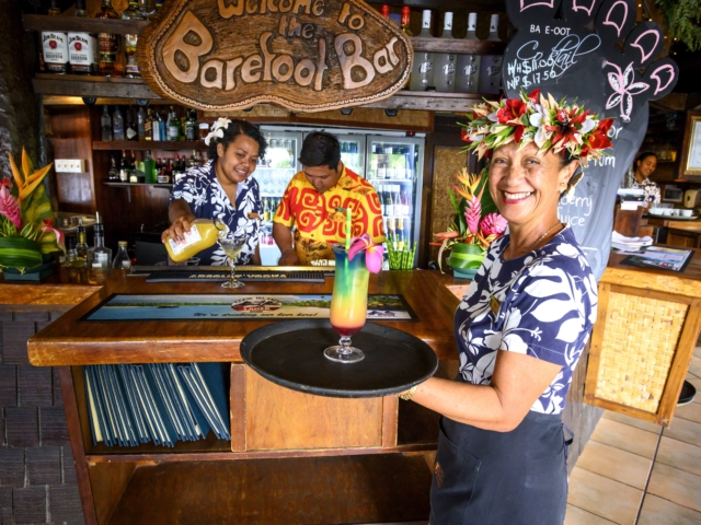 Bartenders smiles along during their cocktail service capturing a neat and tidy background of the Resort bar