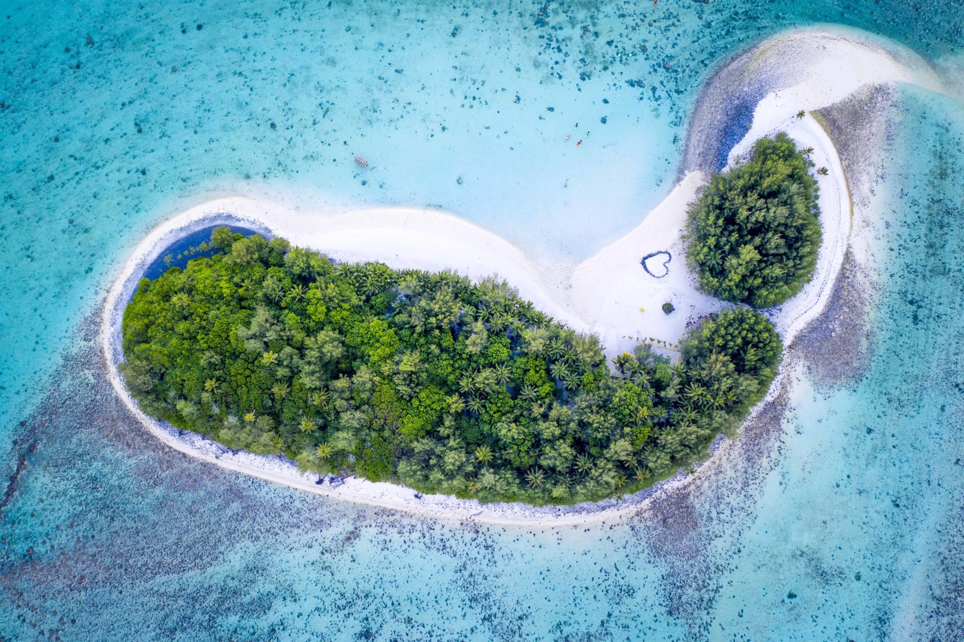 Aerial shot of Motu Koromiri amidst the Muri Blue Lagoon capturing a romantic heart-shaped sign printed on the white-sandy beach