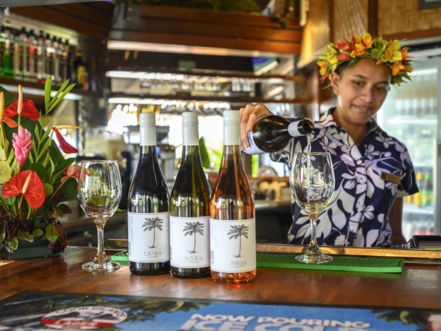 Resort bar attendant showcasing her wine-pouring skills and the variety of wine options available at the bar