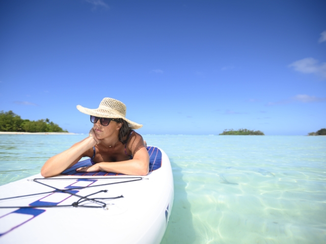 A perfect image of a Resort guest feeling relaxed working on her tan on a floating paddle-board in the Rarotonga lagoon