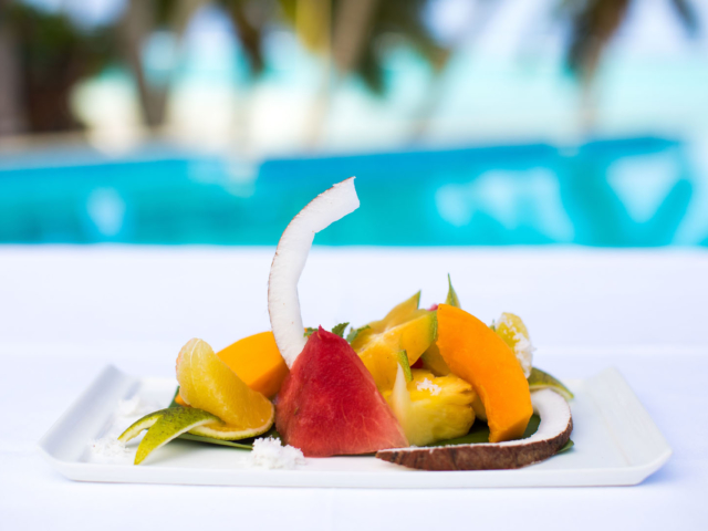 Platter of fresh tropical fruit with a pool view background