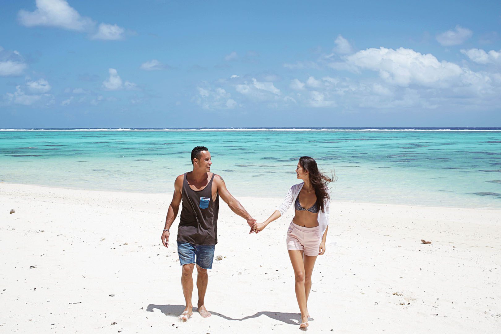 A happy couple hand in hand enjoying a sunny stroll on the beach
