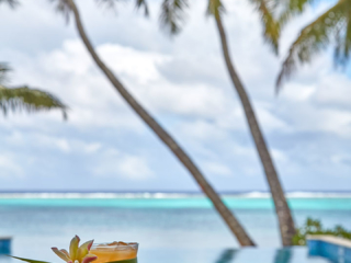 A flower garnished cocktail by the pool overlooking the beach