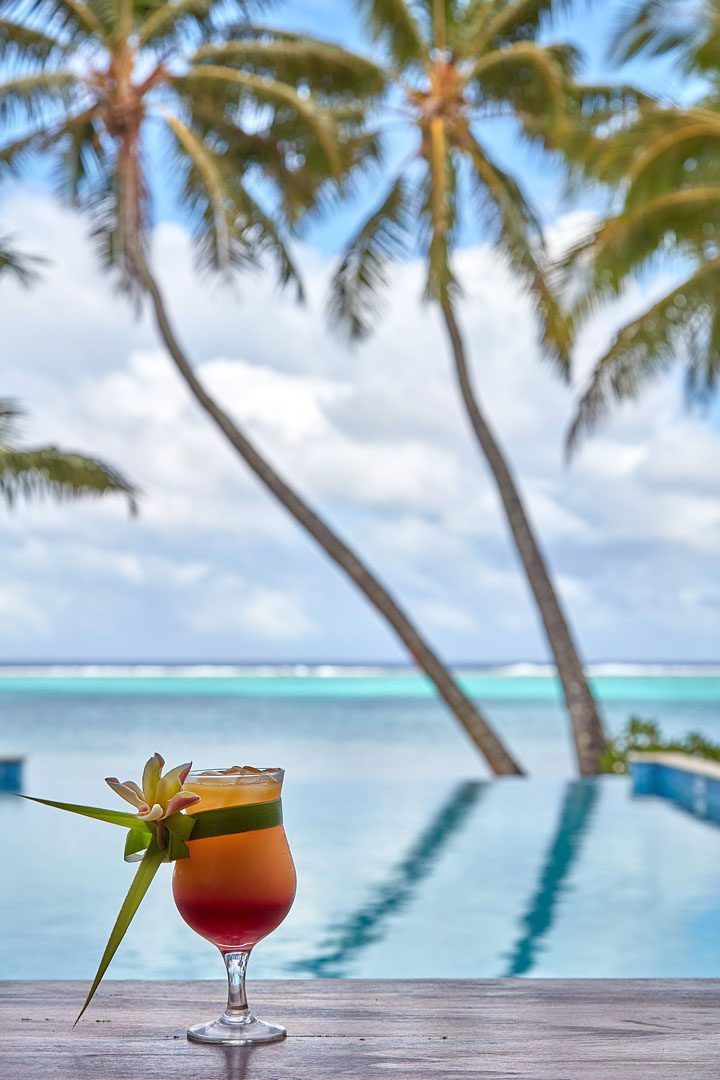 A flower garnished cocktail by the pool overlooking the beach